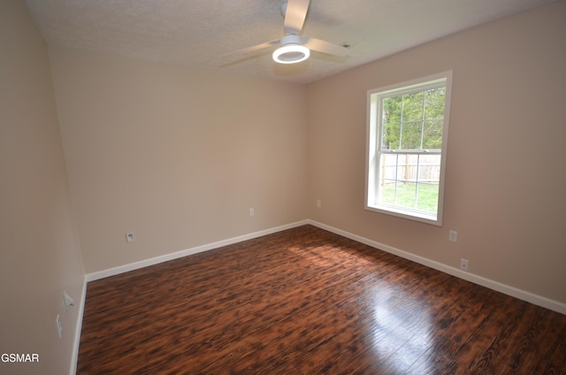 spare room with dark wood-type flooring, a ceiling fan, baseboards, and a textured ceiling