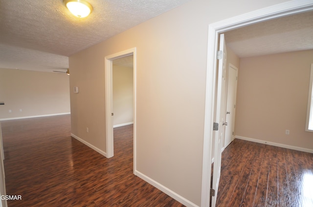 hall with a textured ceiling, baseboards, and wood finished floors