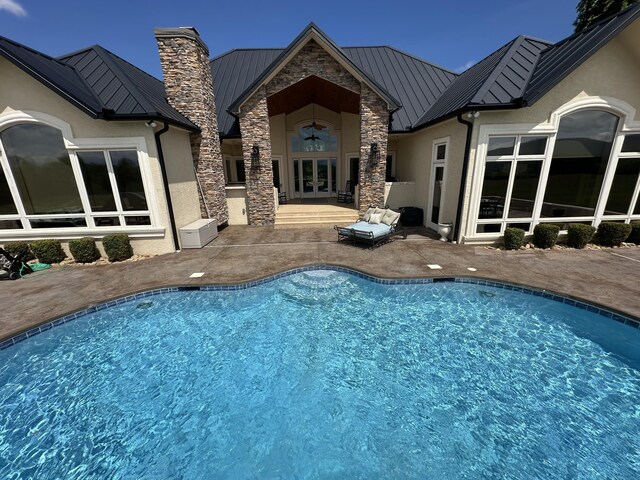 back of house featuring metal roof, stucco siding, french doors, and a standing seam roof