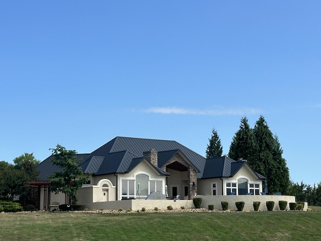 single story home featuring a standing seam roof, a chimney, stucco siding, and metal roof