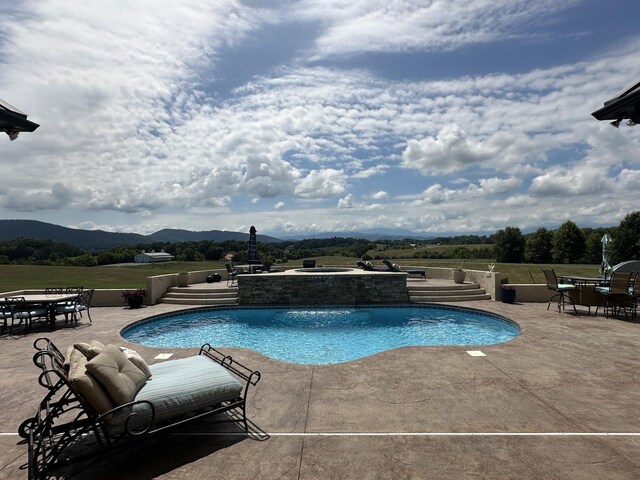 outdoor pool featuring a patio, outdoor dining area, an in ground hot tub, and a mountain view