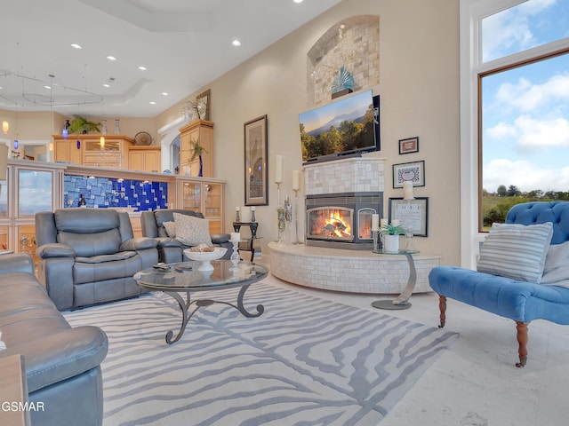 living area with a tiled fireplace, a raised ceiling, and recessed lighting