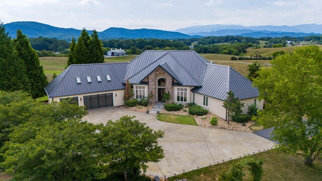 modern inspired farmhouse with stucco siding, concrete driveway, a mountain view, and a standing seam roof
