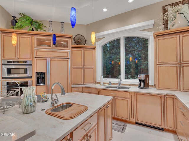 kitchen featuring light stone counters, a sink, paneled refrigerator, and hanging light fixtures