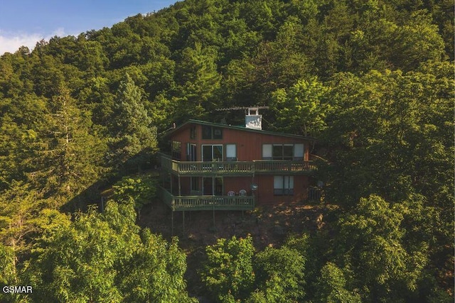 back of property featuring a wooded view