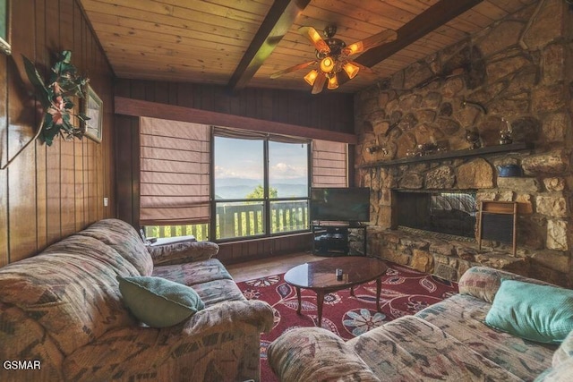 living area featuring beam ceiling, wooden walls, and a fireplace