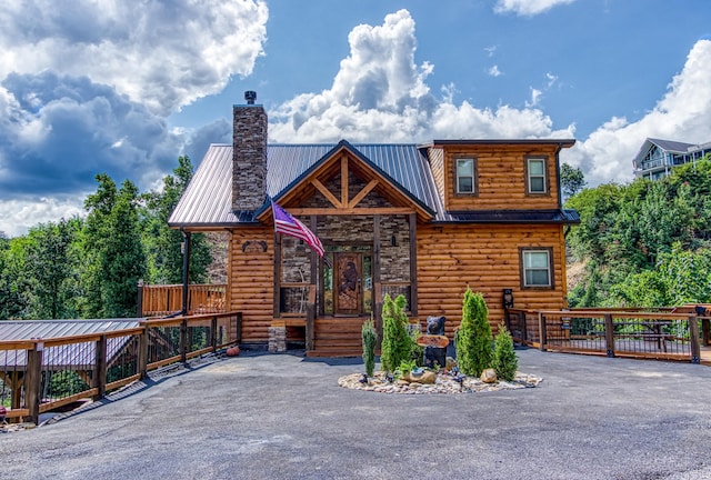 view of front of property with metal roof, a chimney, and log veneer siding