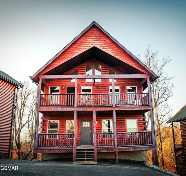 log cabin featuring a balcony, covered porch, and log siding