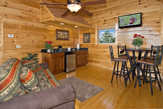 interior space featuring ceiling fan, light hardwood / wood-style flooring, vaulted ceiling, wooden walls, and wood ceiling