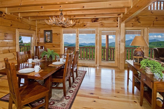 dining space with a mountain view, plenty of natural light, beamed ceiling, and light hardwood / wood-style floors