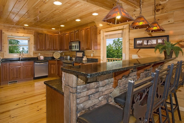 kitchen featuring hanging light fixtures, wooden ceiling, light hardwood / wood-style floors, a breakfast bar, and appliances with stainless steel finishes