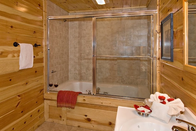 bathroom featuring wood walls, combined bath / shower with glass door, and wooden ceiling