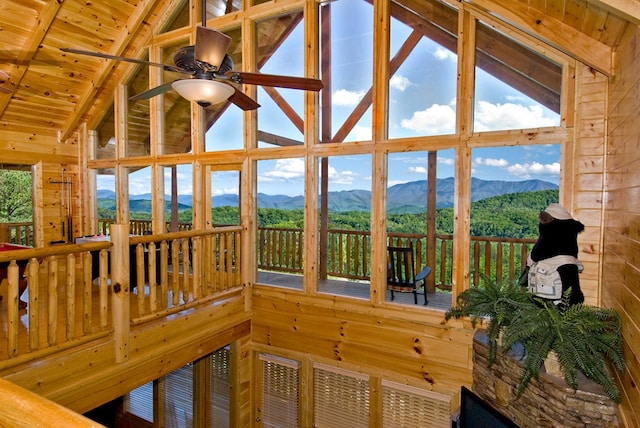 sunroom / solarium featuring a mountain view, vaulted ceiling with beams, ceiling fan, and wooden ceiling