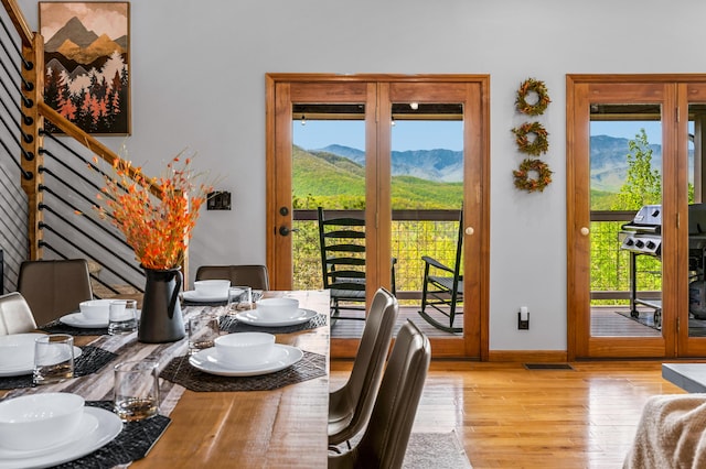 dining space with a mountain view, a healthy amount of sunlight, and light wood-type flooring