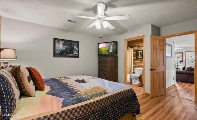 bedroom featuring visible vents, a ceiling fan, a textured ceiling, ensuite bath, and light wood-type flooring