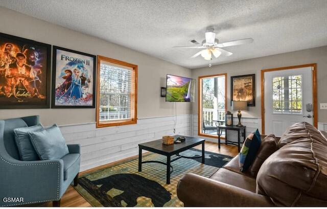 living room featuring a wainscoted wall, a wealth of natural light, and wood finished floors