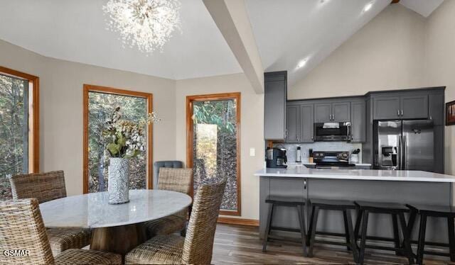 dining space featuring a notable chandelier, plenty of natural light, high vaulted ceiling, and dark wood-type flooring