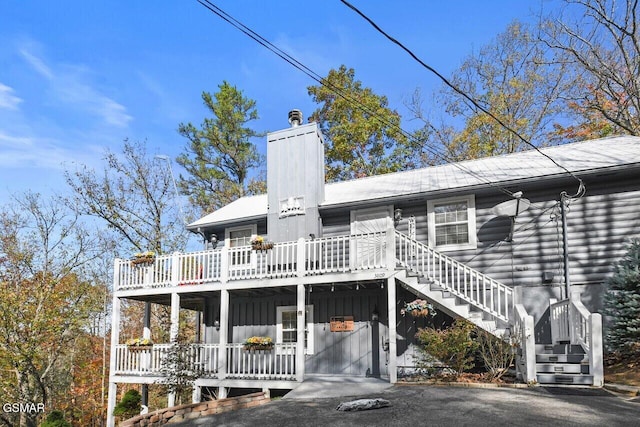 back of house featuring stairway, a chimney, and a wooden deck