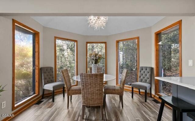 dining area with a wealth of natural light, a notable chandelier, and wood finished floors