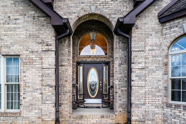 view of exterior entry featuring brick siding
