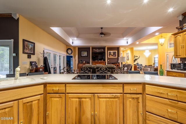 kitchen featuring open floor plan, light countertops, a sink, and black electric cooktop