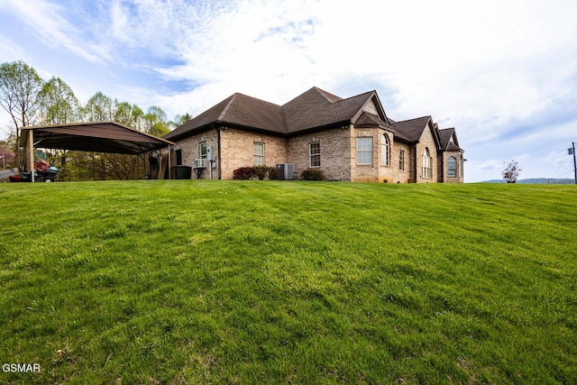 view of home's exterior with a carport, roof with shingles, central air condition unit, brick siding, and a yard