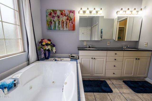 bathroom with double vanity, a sink, a tub with jets, and tile patterned flooring
