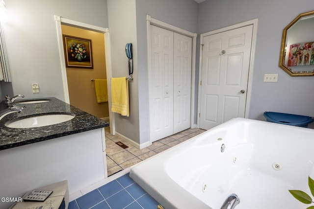 full bathroom with a closet, a sink, a tub with jets, double vanity, and tile patterned floors