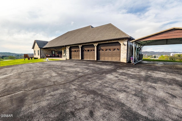 view of home's exterior with roof with shingles, an attached garage, and aphalt driveway
