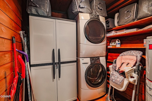 laundry area featuring stacked washer / dryer and cabinet space