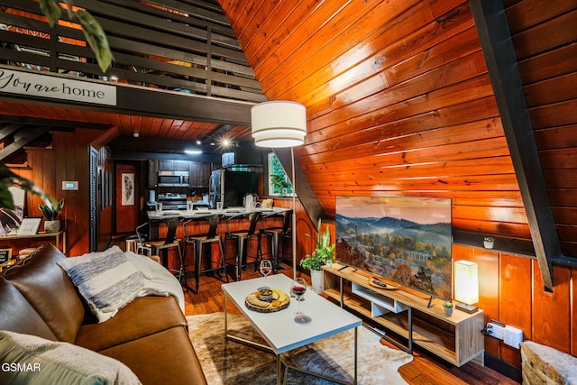 living area with wood finished floors, wooden walls, and vaulted ceiling