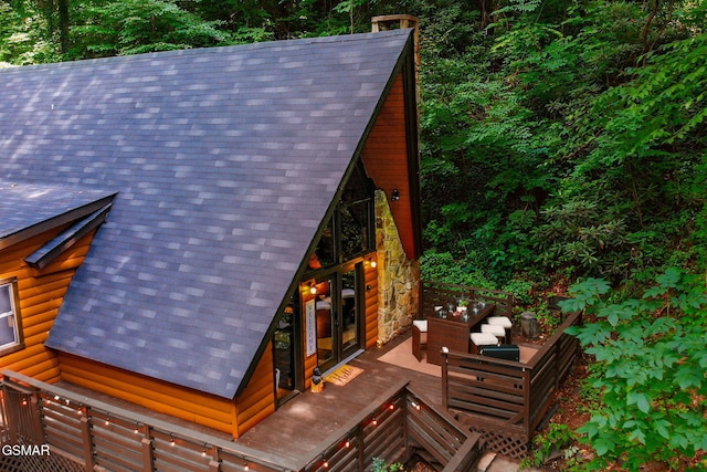 exterior space featuring a shingled roof and an outdoor living space