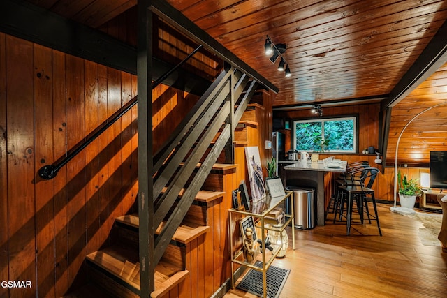 interior space featuring indoor wet bar, rail lighting, wood walls, wood ceiling, and hardwood / wood-style floors