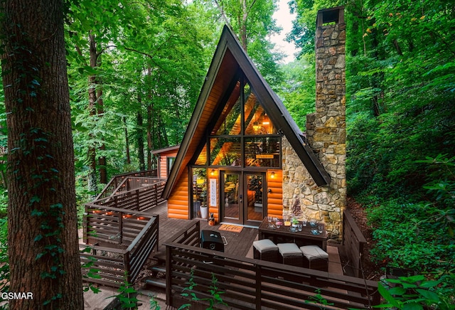 back of property with french doors, faux log siding, and a wooden deck