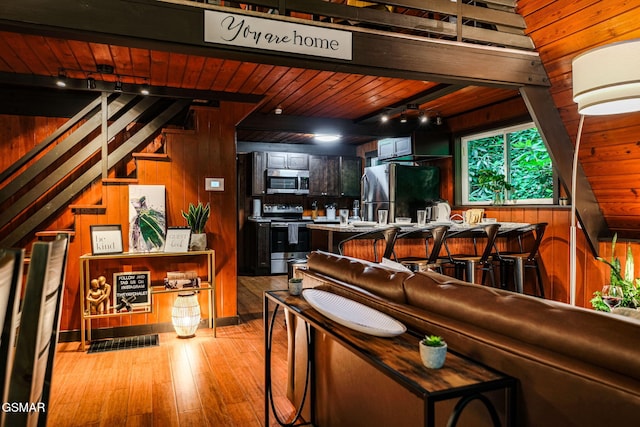 living room featuring track lighting, stairs, wood ceiling, hardwood / wood-style floors, and wood walls