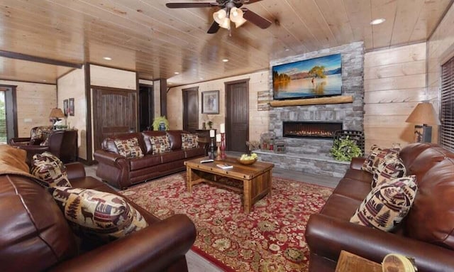 living room with wood finished floors, a stone fireplace, recessed lighting, wooden ceiling, and a ceiling fan