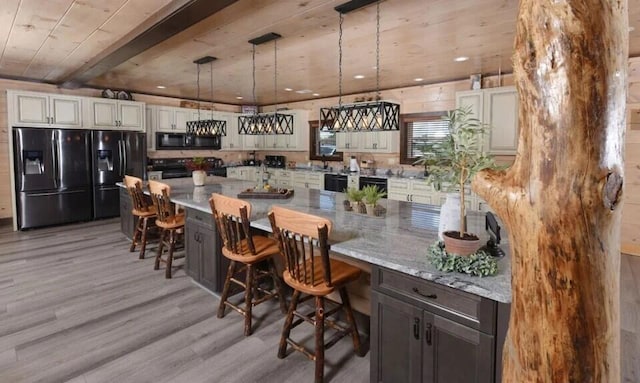 kitchen with hanging light fixtures, light wood-style floors, a breakfast bar area, wood ceiling, and black appliances
