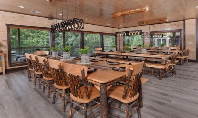 dining space featuring wooden ceiling, wood walls, and wood finished floors