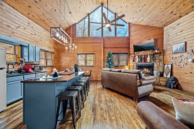 interior space featuring high vaulted ceiling, wooden ceiling, a kitchen breakfast bar, and a fireplace