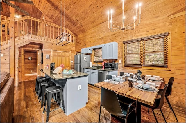 kitchen featuring a notable chandelier, a kitchen island, wooden walls, appliances with stainless steel finishes, and wood ceiling