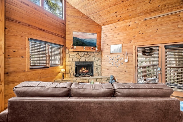 living room featuring wood ceiling, a stone fireplace, and wooden walls