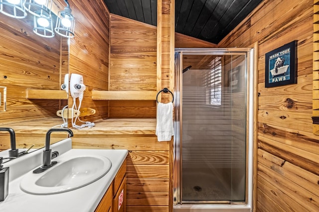 bathroom with an enclosed shower, vanity, vaulted ceiling, and wood walls