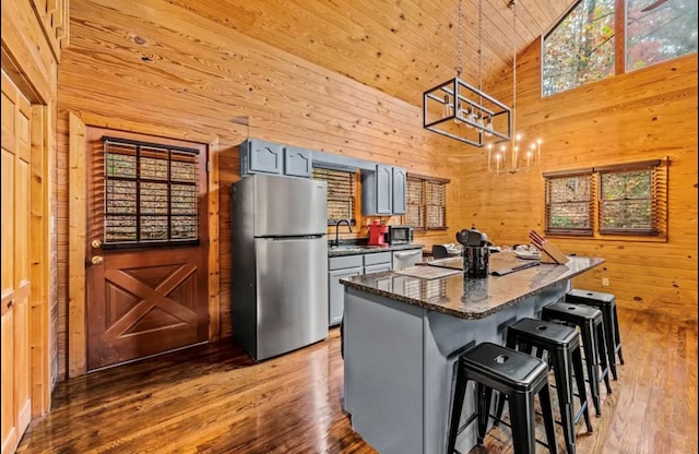 kitchen with appliances with stainless steel finishes, a kitchen island, wooden walls, gray cabinets, and wooden ceiling