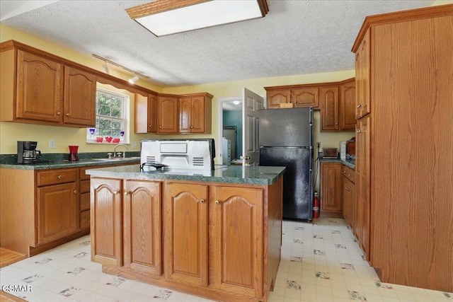 1381 Lake Front Dr, Dandridge, TN 37725 - kitchen with freestanding refrigerator, light floors, a kitchen island, dark countertops, and a textured ceiling