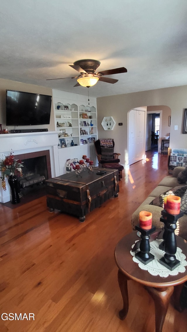 living room featuring ceiling fan, hardwood / wood-style floors, and built in features