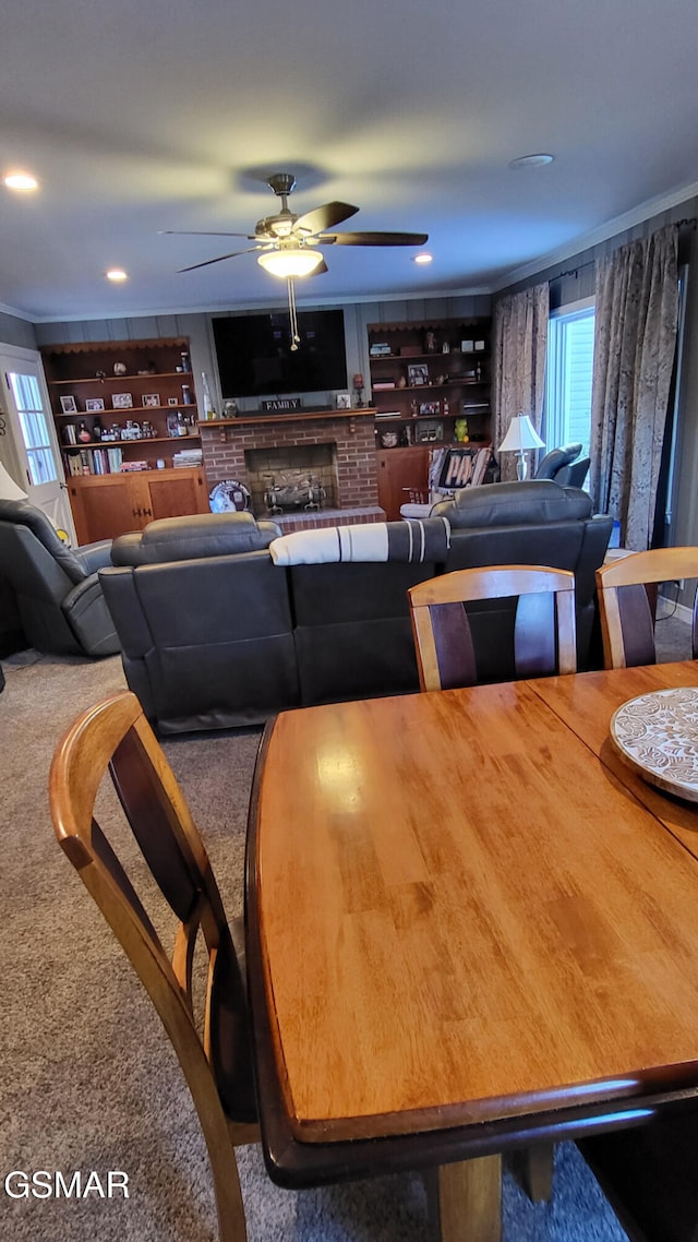 carpeted dining space with a brick fireplace and ceiling fan