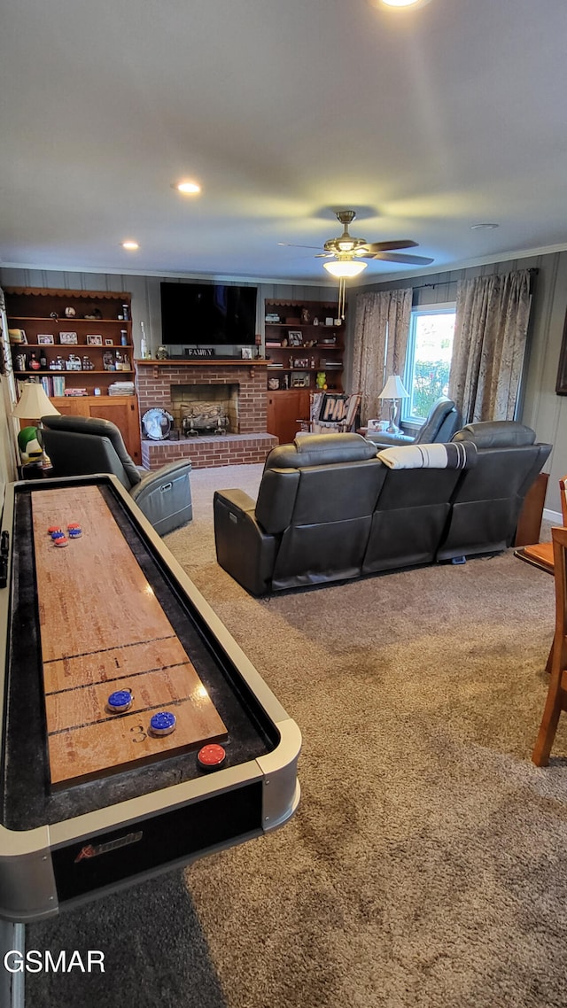 recreation room with ceiling fan, a brick fireplace, and carpet floors