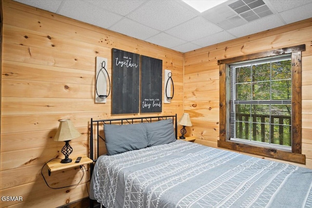 bedroom with a paneled ceiling and wood walls