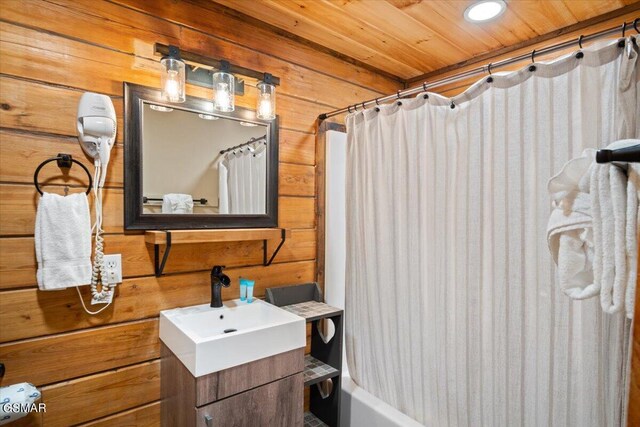 bathroom featuring shower / bath combo with shower curtain, vanity, and wooden walls