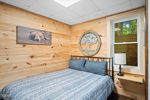 bedroom with a paneled ceiling and wood walls